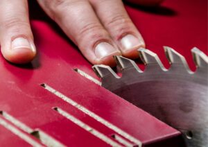 trabalhador exposto ao perigo de acidente com a mão perto da serra de maquinário